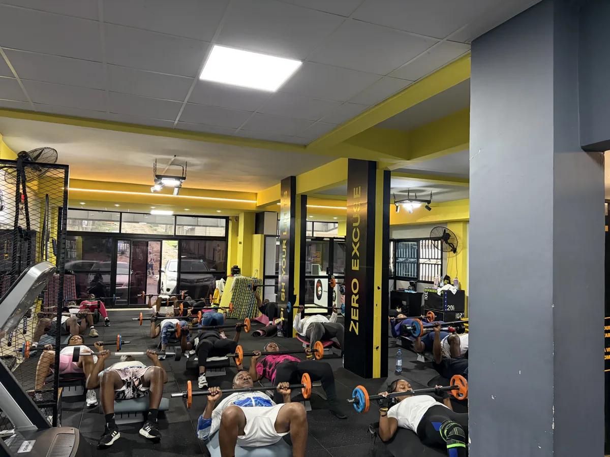 Groupe d'athlètes en plein cross-training dans une salle sombre aux accents jaunes.